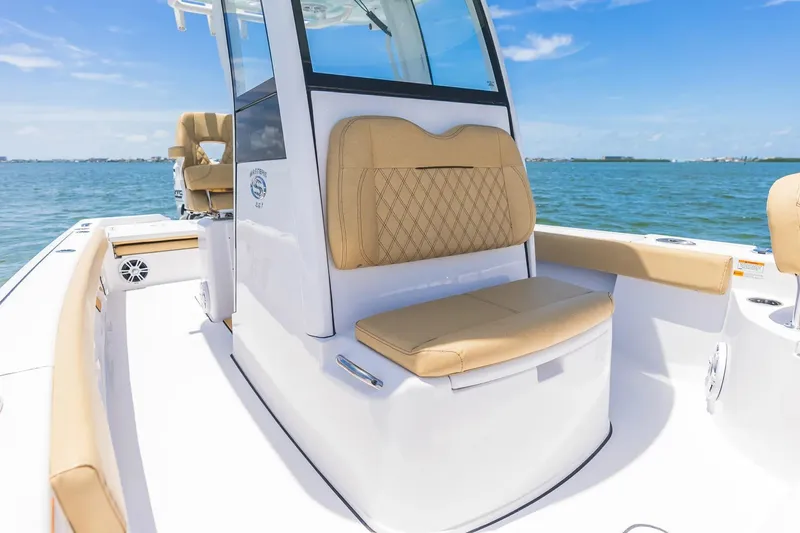 Slide: The Image of 2026 Sportsman Masters 267 Bay Boat interior with tan seating, on calm blue water. - 6