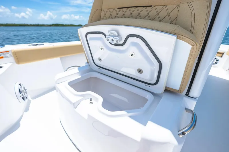 Slide: The Image of 2026 Sportsman Masters 267 Bay Boat with open storage compartment, beige seating, and ocean backdrop. - 7