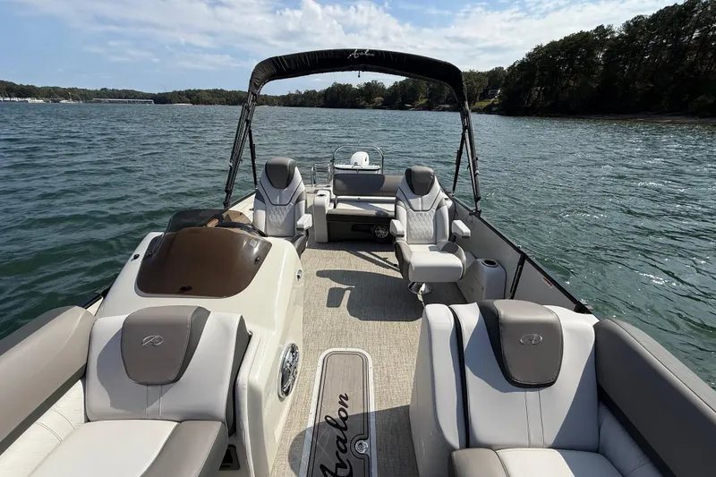 Slide: The Image of 2023 Avalon Catalina Versatile Rear Bench boat on a serene lake, showcasing luxurious seating. - 13
