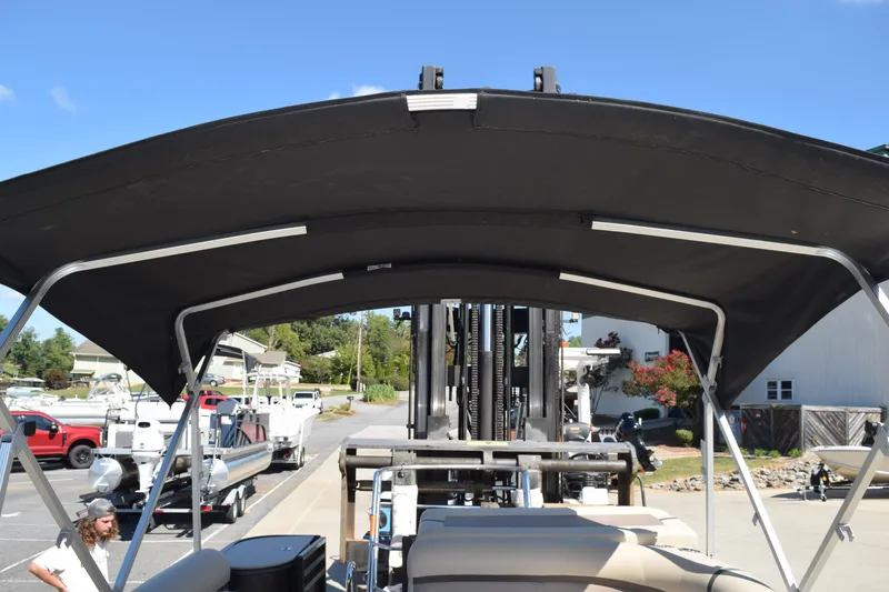 Slide: The Image of 2024 Crest Classic LX 220 L pontoon boat with black canopy, docked under clear blue sky. - 22