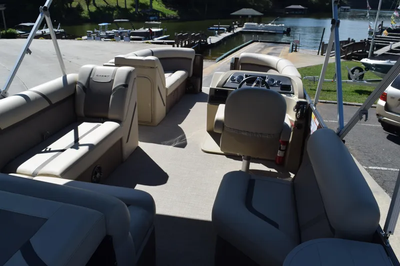 Slide: The Image of 2024 Crest Classic LX 220 L pontoon boat interior with beige seating and steering console. - 6