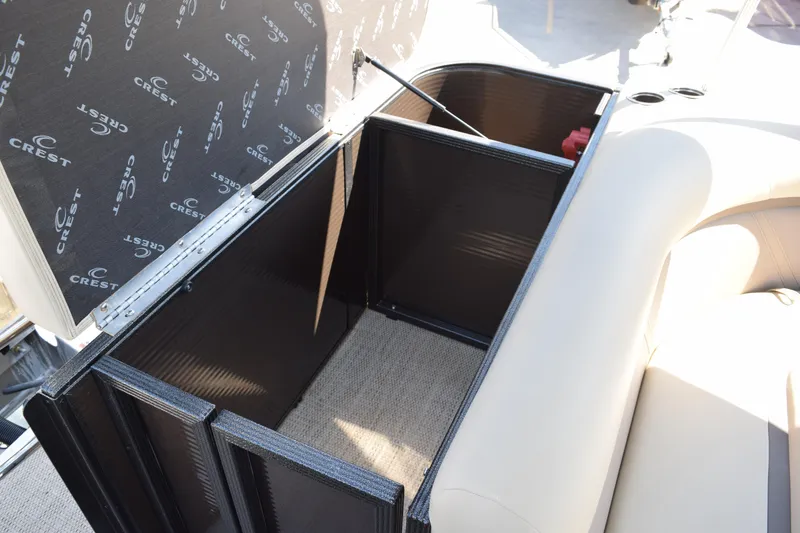 Slide: The Image of 2024 Crest Classic LX 220 L boat storage compartment with open lid and beige seating. - 7