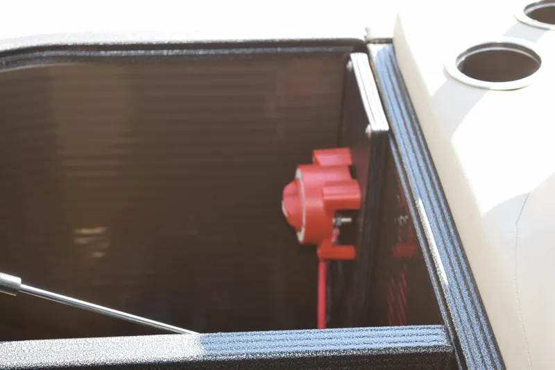 Slide: The Image of 2024 Crest Classic LX 220 L boat storage compartment with red valve and cup holders. - 8