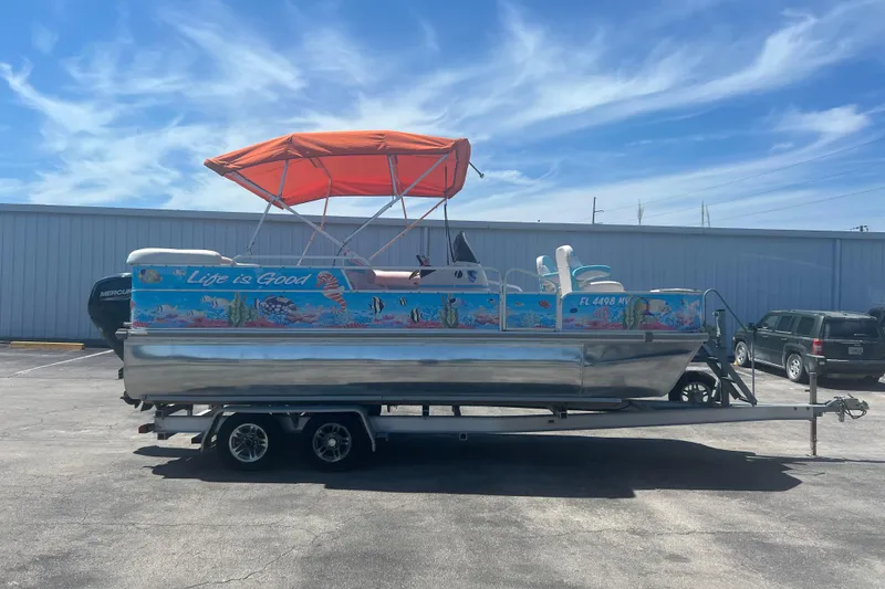 The Image of 2005 G3 LX20 pontoon boat with vibrant marine graphics and orange canopy. - 1