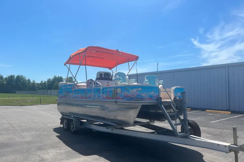 Slide: The Image of 2005 G3 LX20 pontoon boat with vibrant graphics and orange canopy on a trailer. - 2