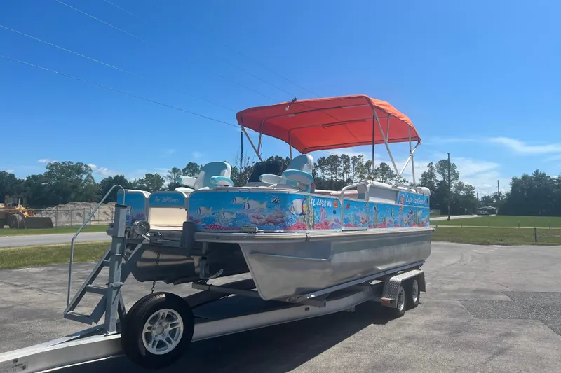 Slide: The Image of 2005 G3 LX20 pontoon boat with orange canopy on trailer, vibrant aquatic graphics. - 4