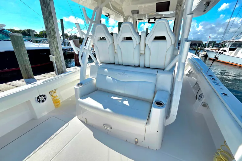 Slide: The Image of 2022 Regulator 37 boat interior with white seating and cup holders at a marina. - 6