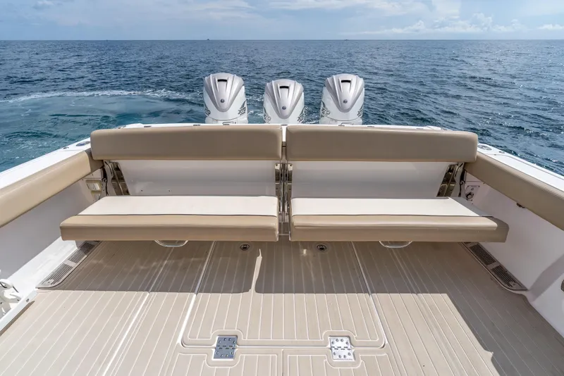 Slide: The Image of 2021 Everglades 395 Center Console boat with triple engines, beige seating, and ocean backdrop. - 51