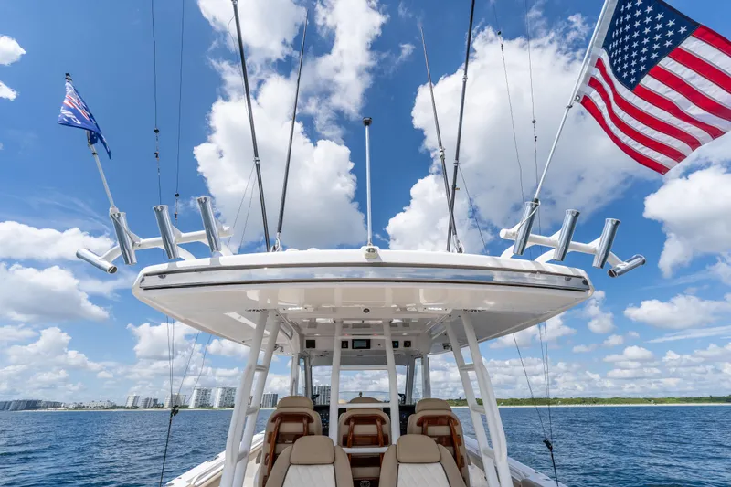 Slide: The Image of 2021 Everglades 395 Center Console boat with flags, under a bright blue sky. - 70