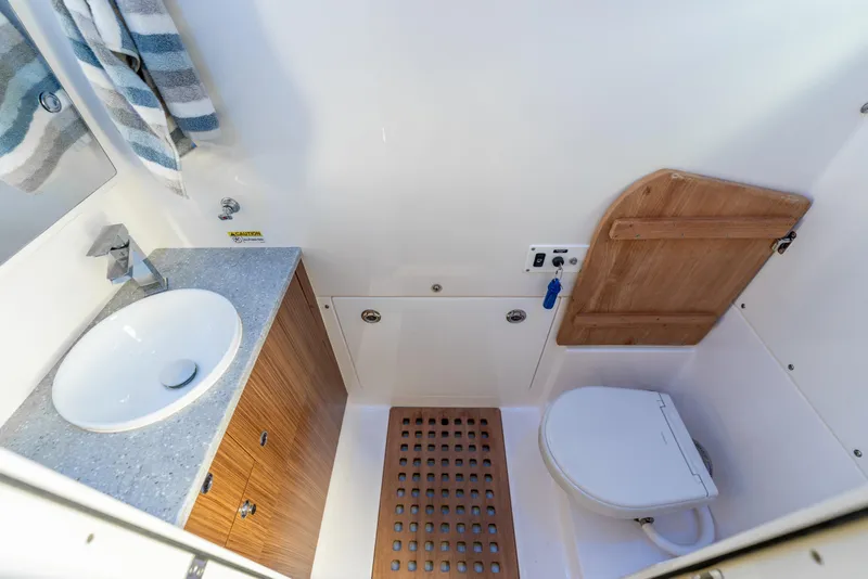 Slide: The Image of 2021 Everglades 395 Center Console bathroom with sink, toilet, and wooden accents. - 82
