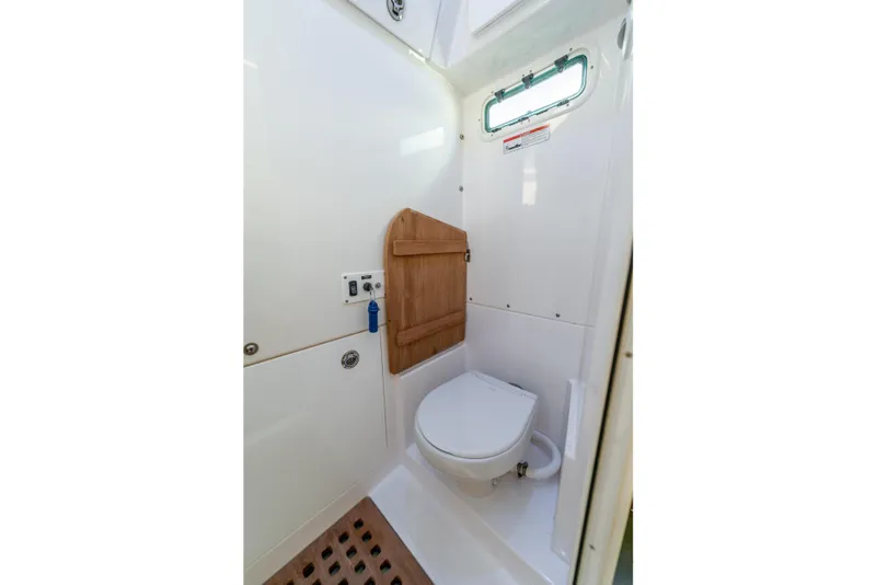 Slide: The Image of 2021 Everglades 395 Center Console boat bathroom with compact toilet and wooden accents. - 83