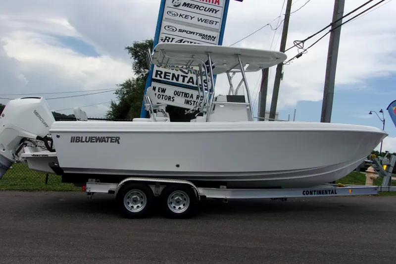 Slide: The Image of 2025 Bluewater 23 T boat on trailer, displayed outdoors with Mercury engine. - 17