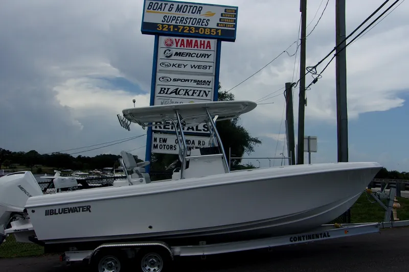 Slide: The Image of 2025 Bluewater 23 T boat on trailer at dealership, cloudy sky background. - 2
