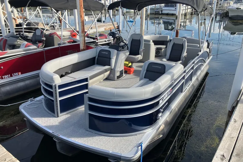 The Image of 2025 Harris Cruiser 230 pontoon boat docked at marina, featuring spacious seating and sleek design. - 0