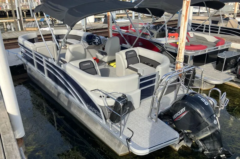 Slide: The Image of 2025 Harris Cruiser 230 pontoon boat docked, featuring a Mercury outboard motor and spacious seating. - 4