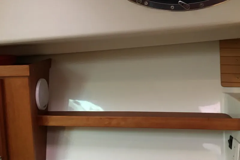 Slide: The Image of Interior of 2008 Back Cove 33 Hard Top Express, featuring wooden shelf and porthole. - 26