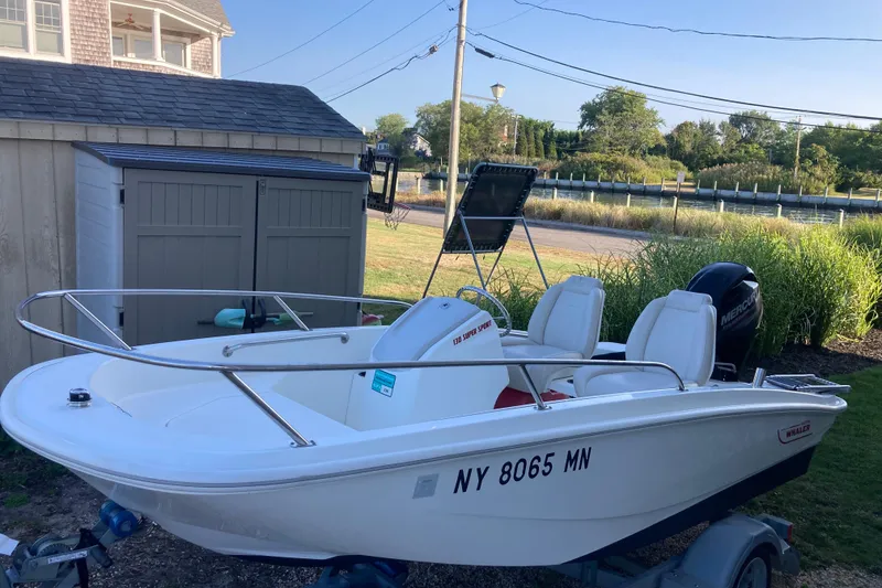 The Image of 2019 Boston Whaler 130 Super Sport boat parked near a shed, ready for adventure. - 0