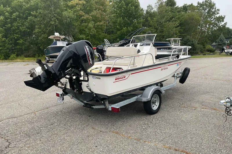 Slide: The Image of 2024 Boston Whaler 150 Montauk boat on trailer, parked outdoors. - 7