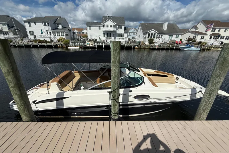 The Image of 2014 Sea Ray 260 Sundeck boat docked by waterfront homes under cloudy sky. - 1