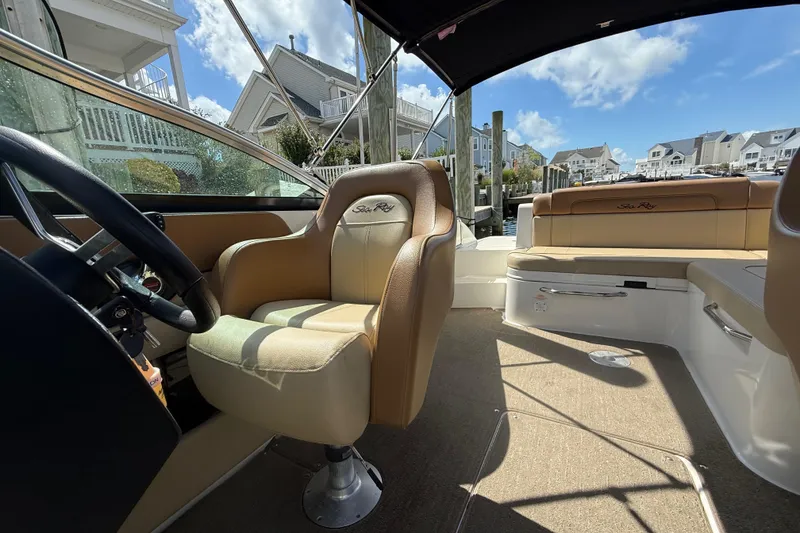 Slide: The Image of 2014 Sea Ray 260 Sundeck interior with tan seating, docked near waterfront homes. - 11