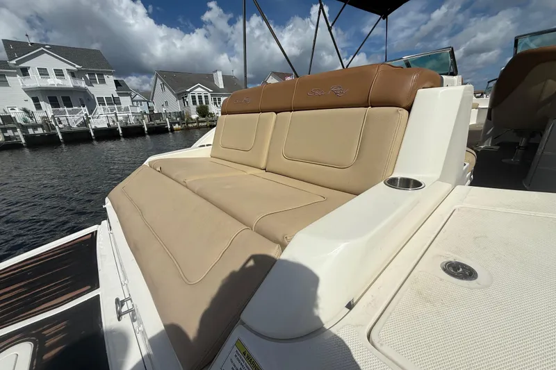 Slide: The Image of 2014 Sea Ray 260 Sundeck boat with tan seating, docked near waterfront homes. - 14