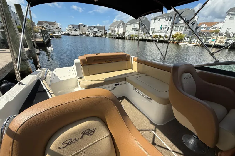 Slide: The Image of 2014 Sea Ray 260 Sundeck boat interior with tan seating, docked in a residential canal. - 19