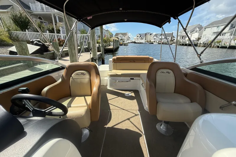 Slide: The Image of 2014 Sea Ray 260 Sundeck interior with tan seating, docked by waterfront homes. - 2