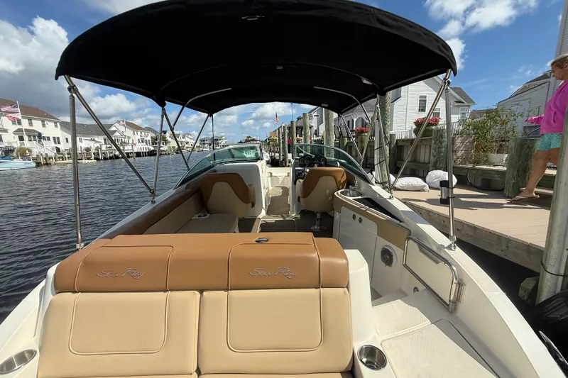 Slide: The Image of 2014 Sea Ray 260 Sundeck boat docked, featuring spacious seating and canopy under a sunny sky. - 6