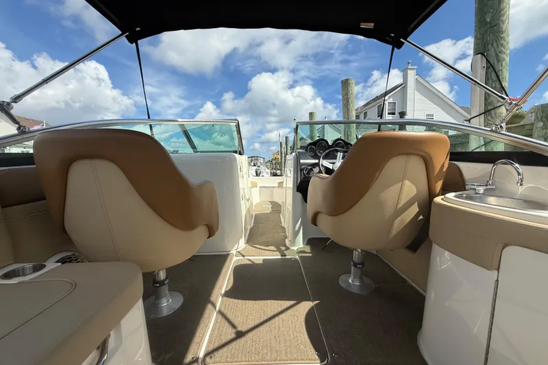 Slide: The Image of 2014 Sea Ray 260 Sundeck interior with tan seating and dashboard, under a blue sky. - 8