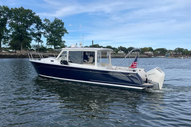 The Image of 2023 MJM 35 boat cruising on a calm lake with trees in the background. - 0
