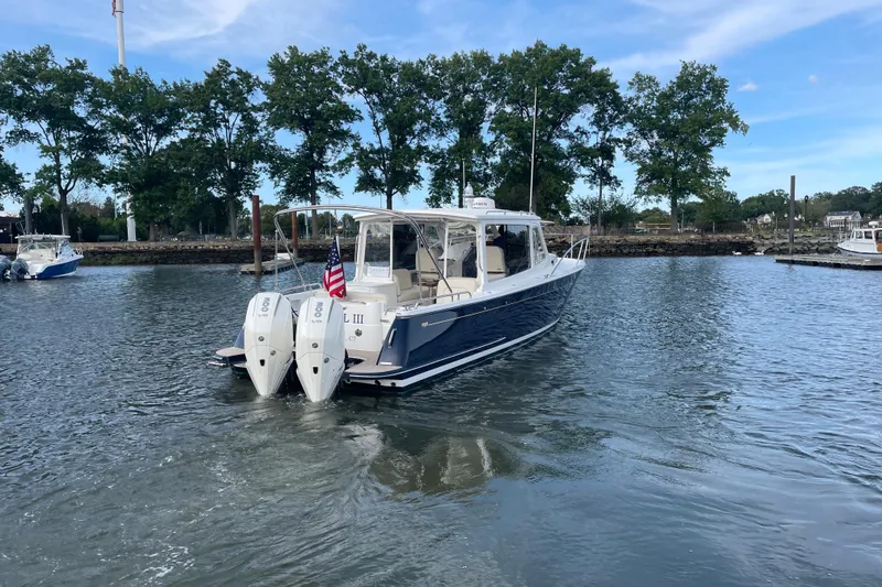 Slide: The Image of 2023 MJM 35 boat with dual engines on a calm waterway, surrounded by trees. - 3