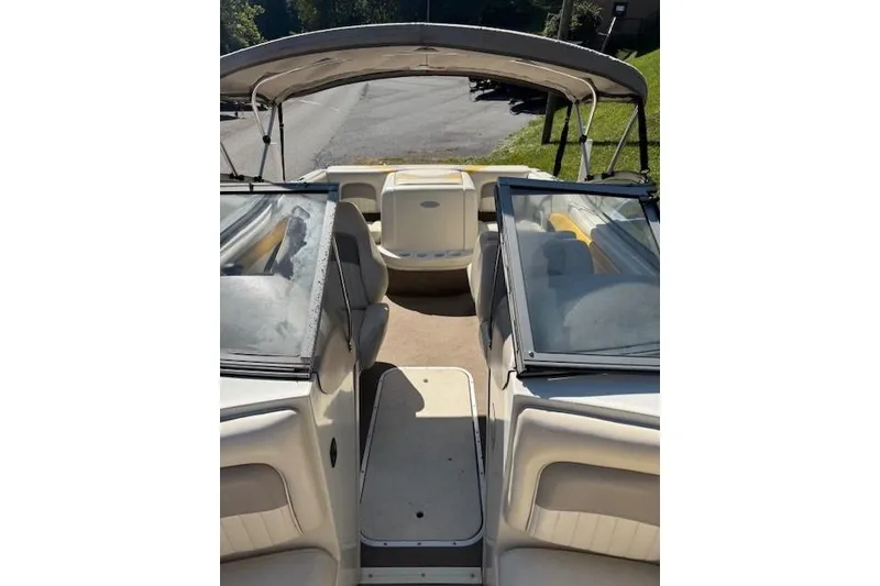 Slide: The Image of 2003 Stingray 180LS boat interior with seating and canopy, parked on a sunny day. - 2