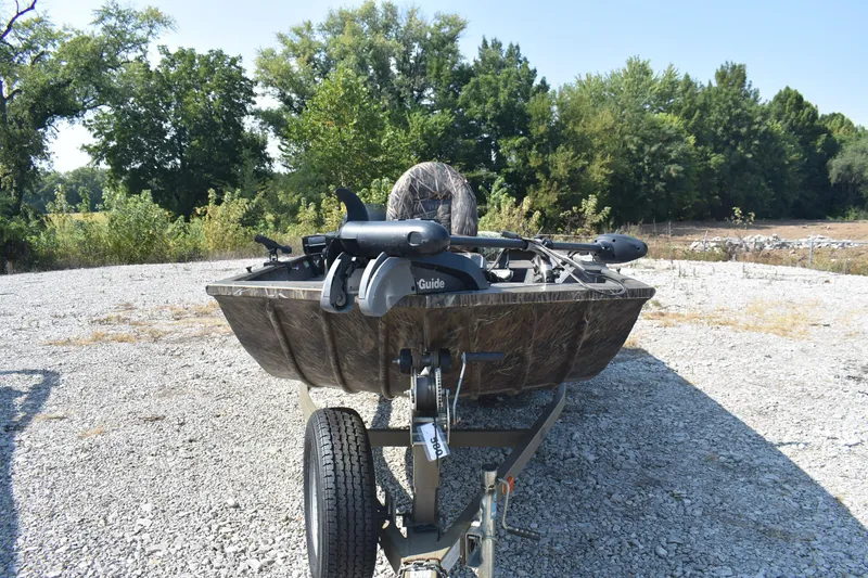 Slide: The Image of 2012 G3 1860 SC CAMO boat on trailer, parked outdoors with trees in background. - 2