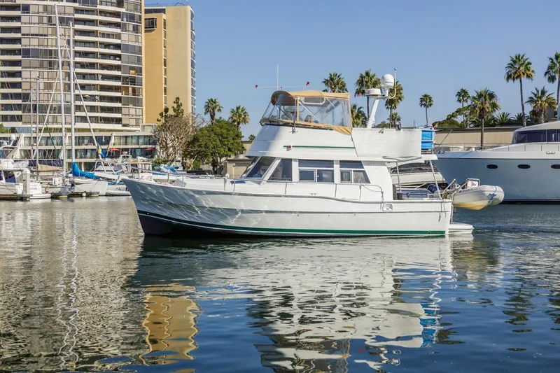 Slide: The Image of 2001 Mainship 390 Trawler docked in marina, surrounded by palm trees and buildings. - 1