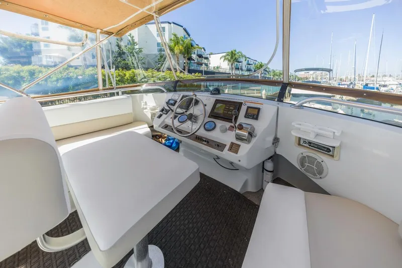 Slide: The Image of 2001 Mainship 390 Trawler helm with modern controls, docked in a sunny marina. - 16