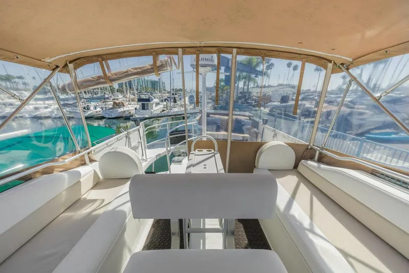 Slide: The Image of 2001 Mainship 390 Trawler interior with marina view, featuring comfortable seating and clear canopy. - 18