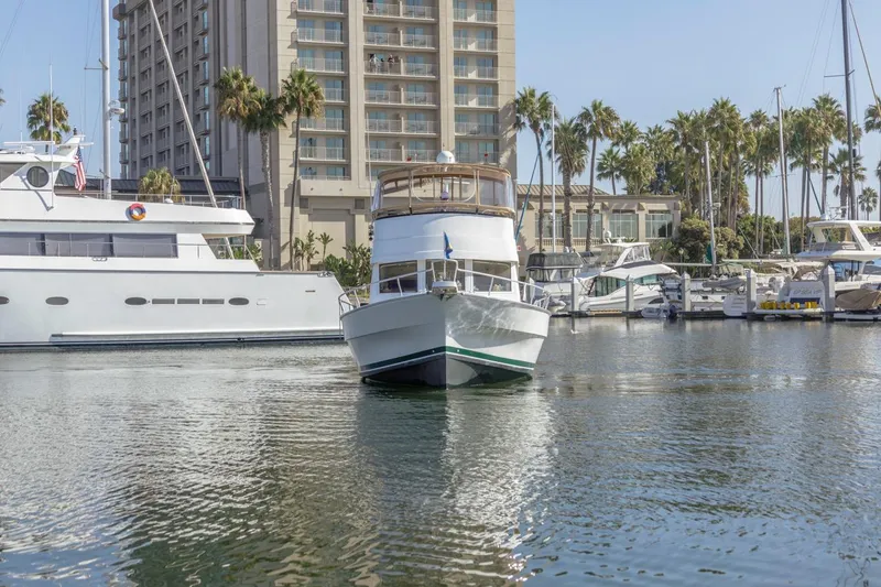 Slide: The Image of 2001 Mainship 390 Trawler docked in marina with palm trees and buildings. - 2