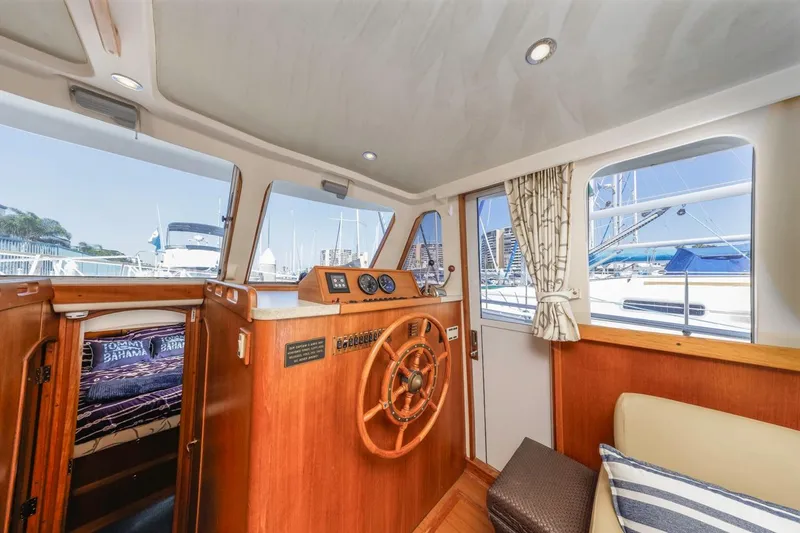 Slide: The Image of 2001 Mainship 390 Trawler interior with helm, wooden accents, and marina view. - 26