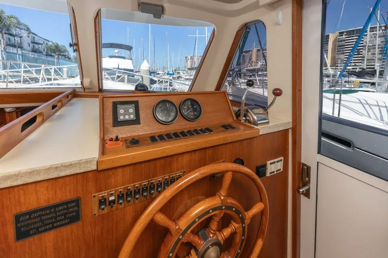 Slide: The Image of 2001 Mainship 390 Trawler helm with wooden wheel and marina view. - 27