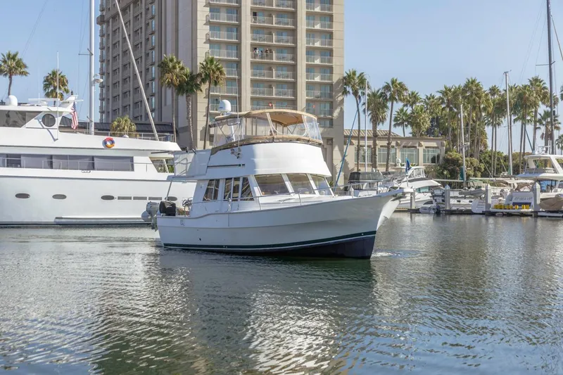 Slide: The Image of 2001 Mainship 390 Trawler in marina, surrounded by yachts and palm trees. - 3
