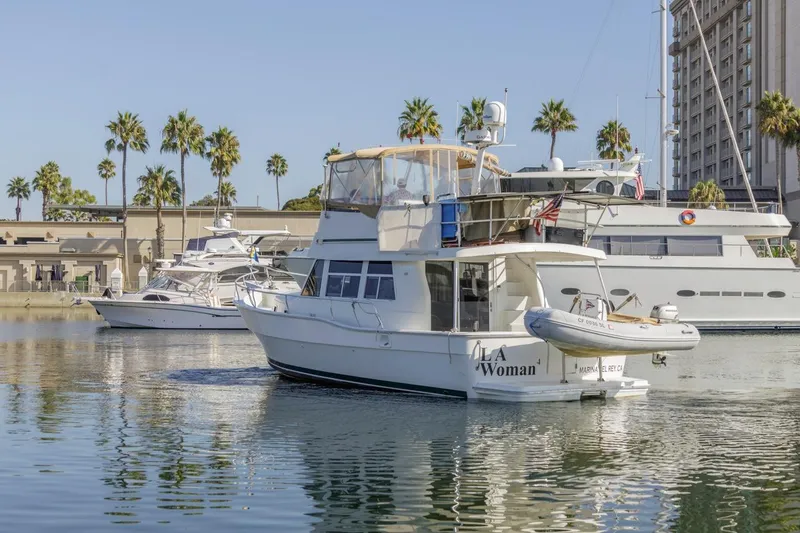Slide: The Image of 2001 Mainship 390 Trawler in marina, surrounded by palm trees and other boats. - 5