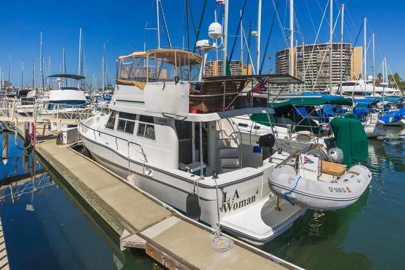 Slide: The Image of 2001 Mainship 390 Trawler docked at marina, surrounded by sailboats under clear blue sky. - 6
