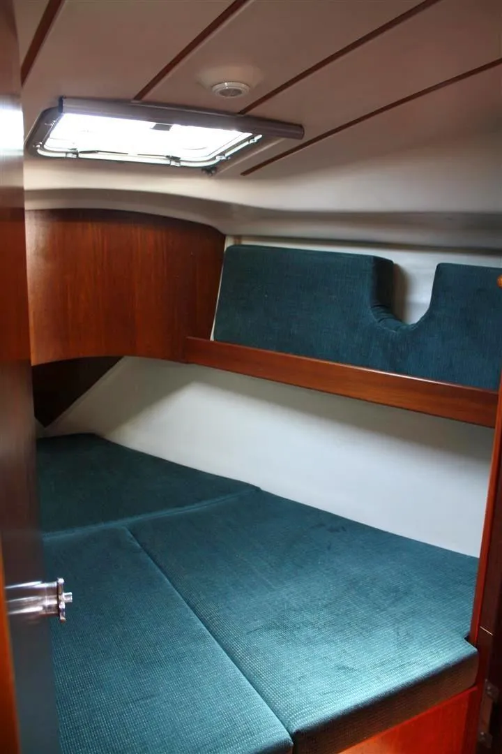 Slide: The Image of 1999 Beneteau Oceanis 352 cabin interior with teal upholstery and wooden accents. - 18