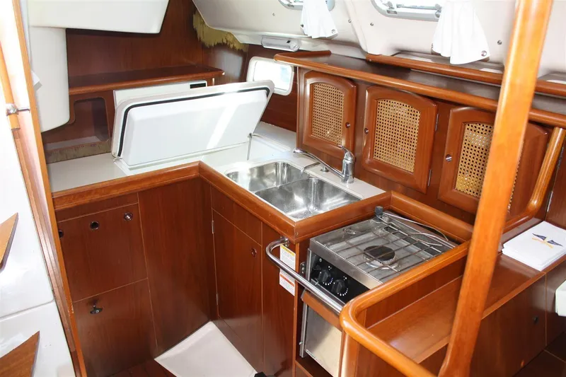 Slide: The Image of 1999 Beneteau Oceanis 352 yacht kitchen with wood cabinetry, sink, and stove. - 19