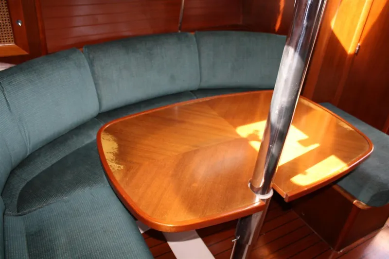 Slide: The Image of Interior of 1999 Beneteau Oceanis 352 sailboat with wooden table and cushioned seating. - 28