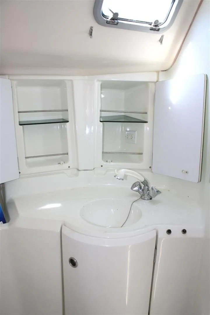 Slide: The Image of 1999 Beneteau Oceanis 352 bathroom with sink, mirror, and storage shelves. - 32