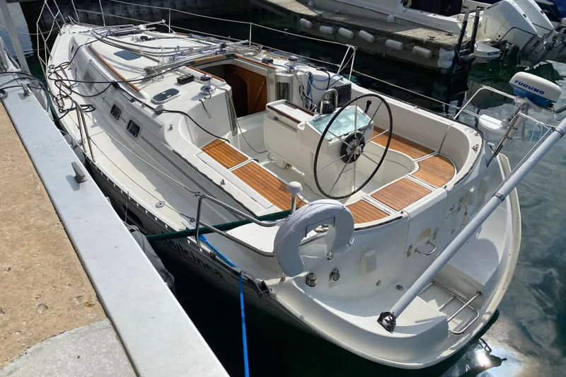 Slide: The Image of 1999 Beneteau Oceanis 352 sailboat docked, featuring a spacious cockpit and wooden deck accents. - 5