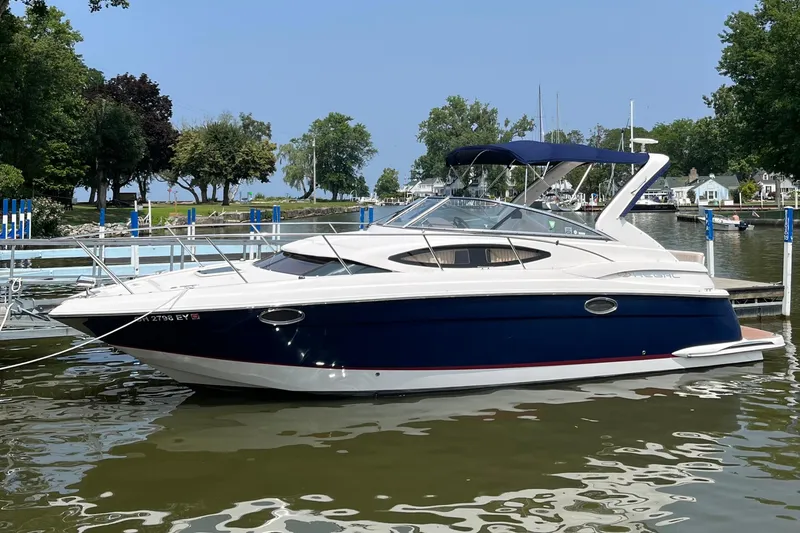 The Image of 2011 Regal 3060 Express Cruiser docked on a calm lake with trees in the background. - 0