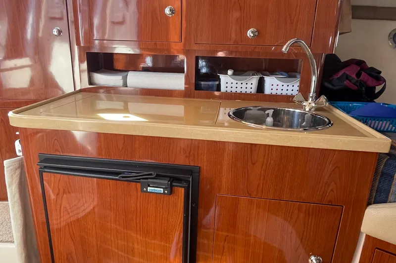 Slide: The Image of 2011 Regal 3060 Express Cruiser interior with wooden cabinetry and compact kitchenette. - 19