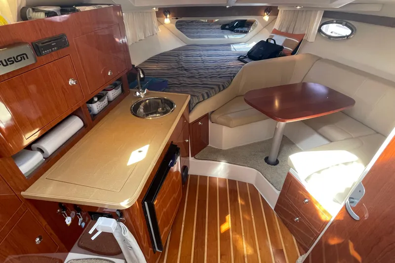 Slide: The Image of 2011 Regal 3060 Express Cruiser interior with beige seating, wooden table, and mounted TV. - 20